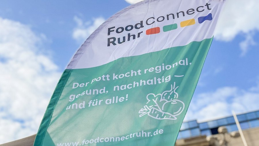Fahne mit Schriftzug vor einem blauen Himmel