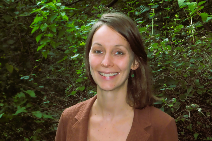 Bild von einer Frau, die vor grünem Blattwerk steht
